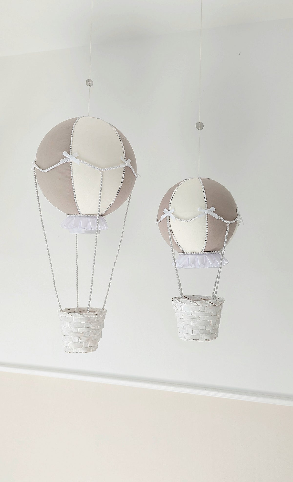 A set of handcrafted nursery balloons in neutral tones, trimmed with bows and ready to drift into little daydreams.