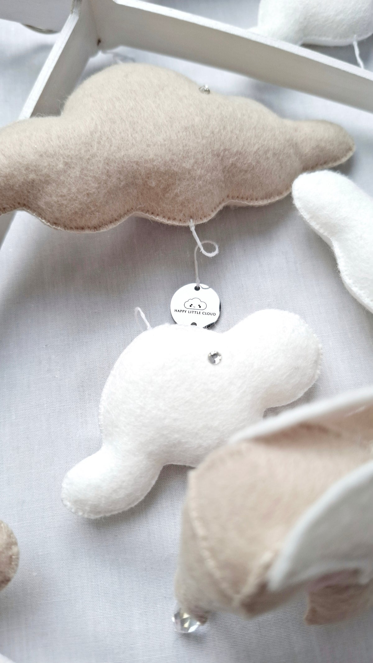 Close-up of handmade beige and white elephant mobile with gentle textures and crystal droplets, perfect for calm, neutral nurseries.