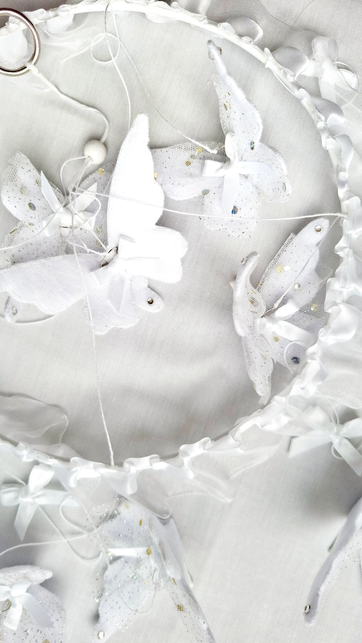 Minimalist white butterfly mobile with floating textures and soft silhouettes, designed for gentle movement and calm.
