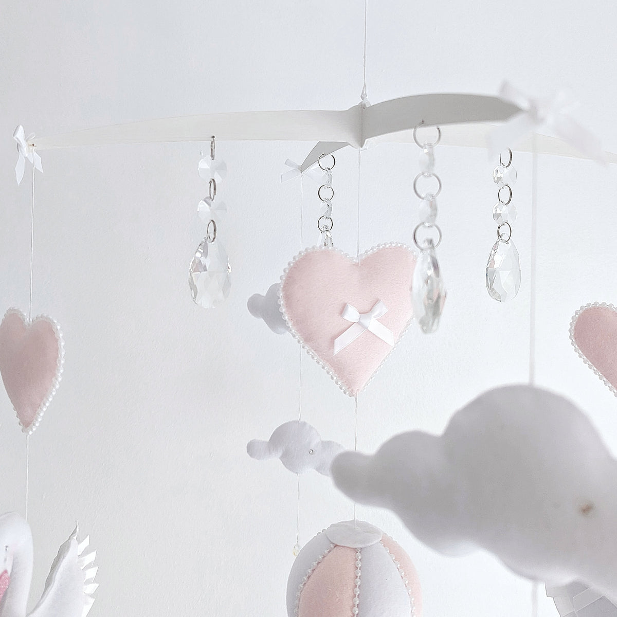 Refined swan wall hanging with a flower crown and trailing hearts, ideal for elegant nursery decor.