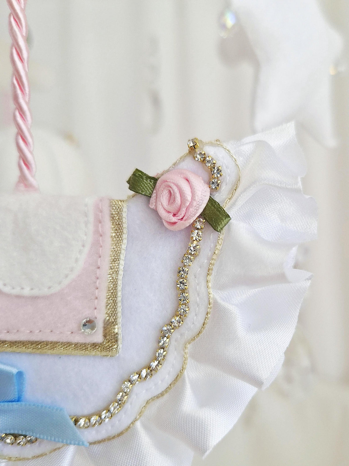 Detailed close-up of the handmade felt saddle with blush pink rose, gold trim and decorative embellishments.