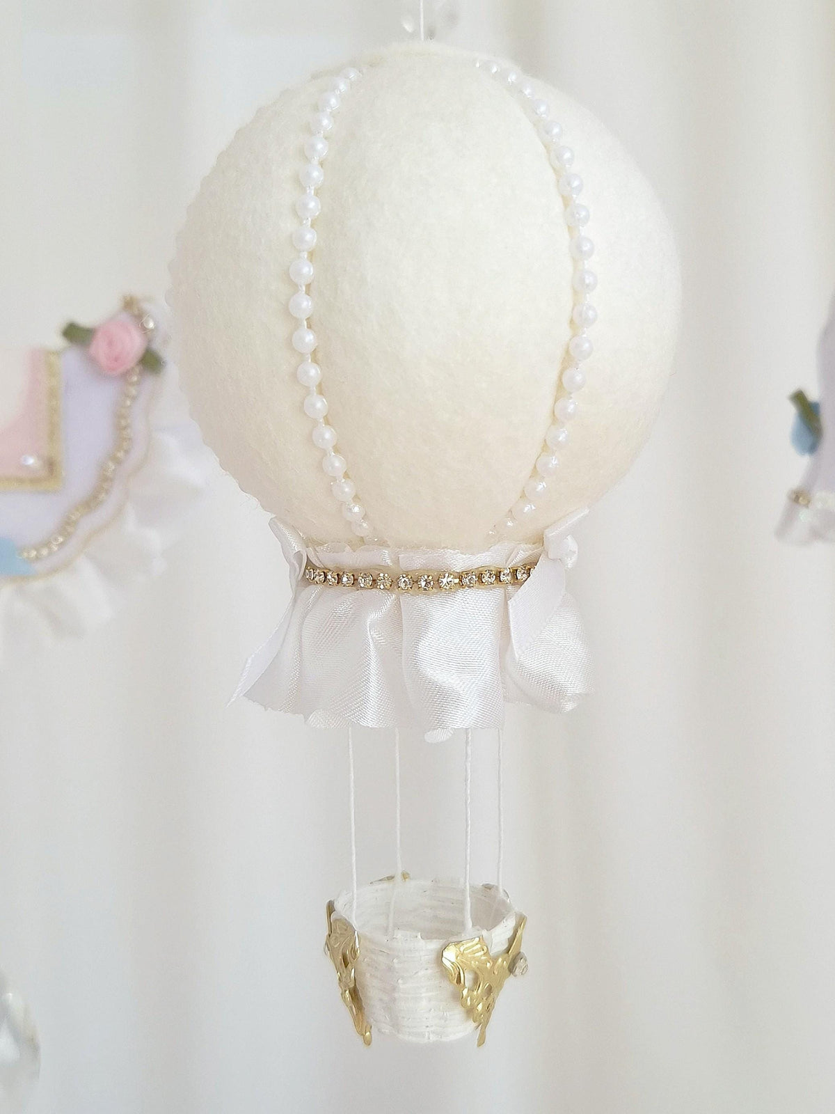 Close-up of the handmade felt hot air balloon with stitched panels, gold trim and hanging glass crystal.