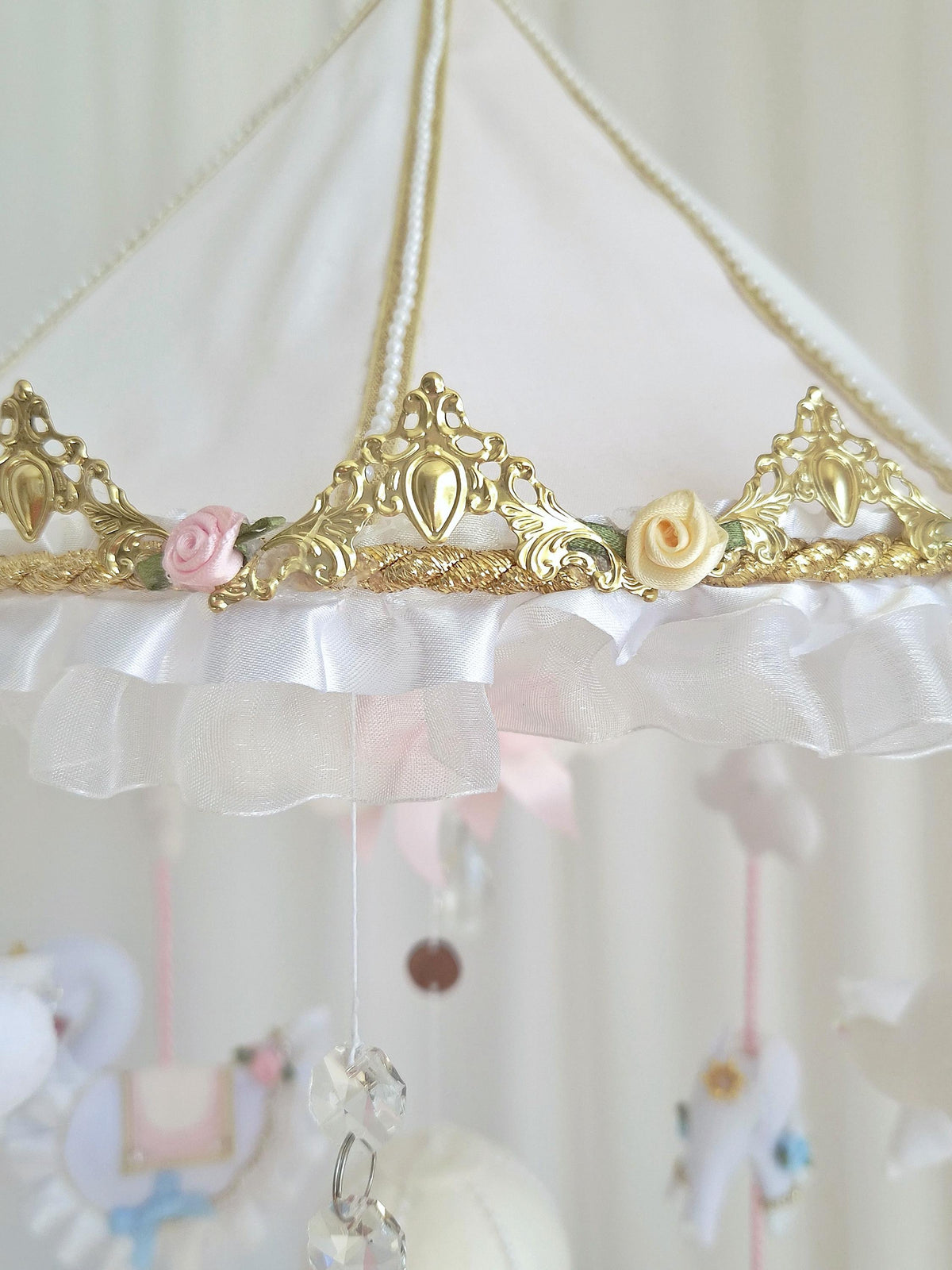 Decorative gold and white carousel canopy with floral embellishments supporting the handmade felt baby mobile.