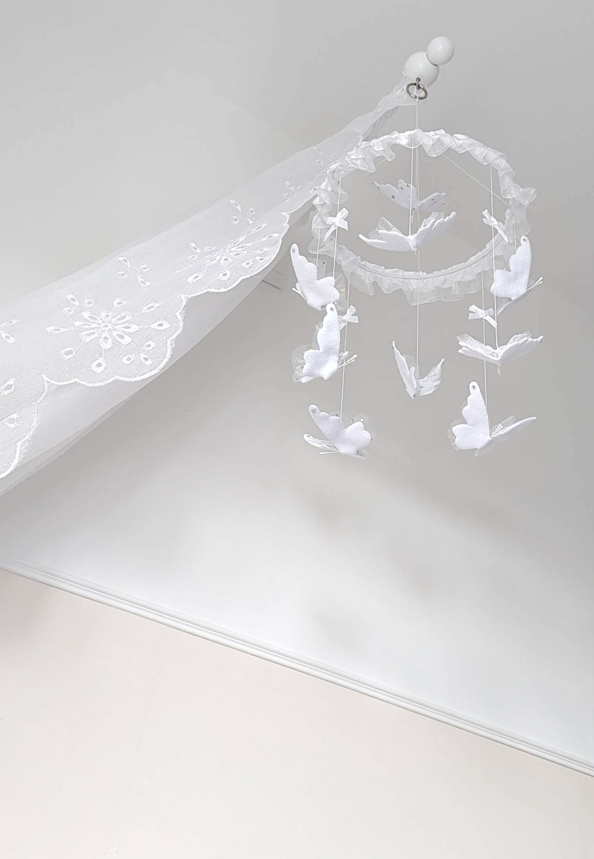 Delicate butterfly baby mobile in all white, handcrafted with soft lace wings and ruffled trim for a pure, peaceful nursery.

