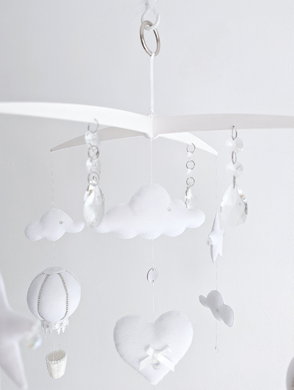 Delicate handmade baby mobile with white hot air balloons, fluffy clouds, and dreamy sky elements for a modern luxury nursery.

