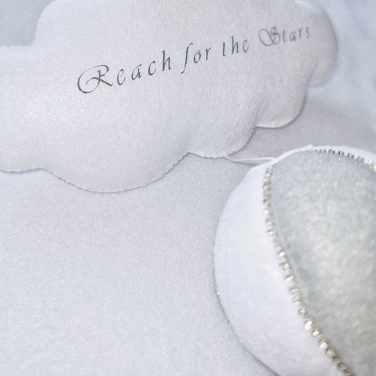 Close-up of handmade felt textures on a white and grey nursery balloon with embroidered cloud accent.
