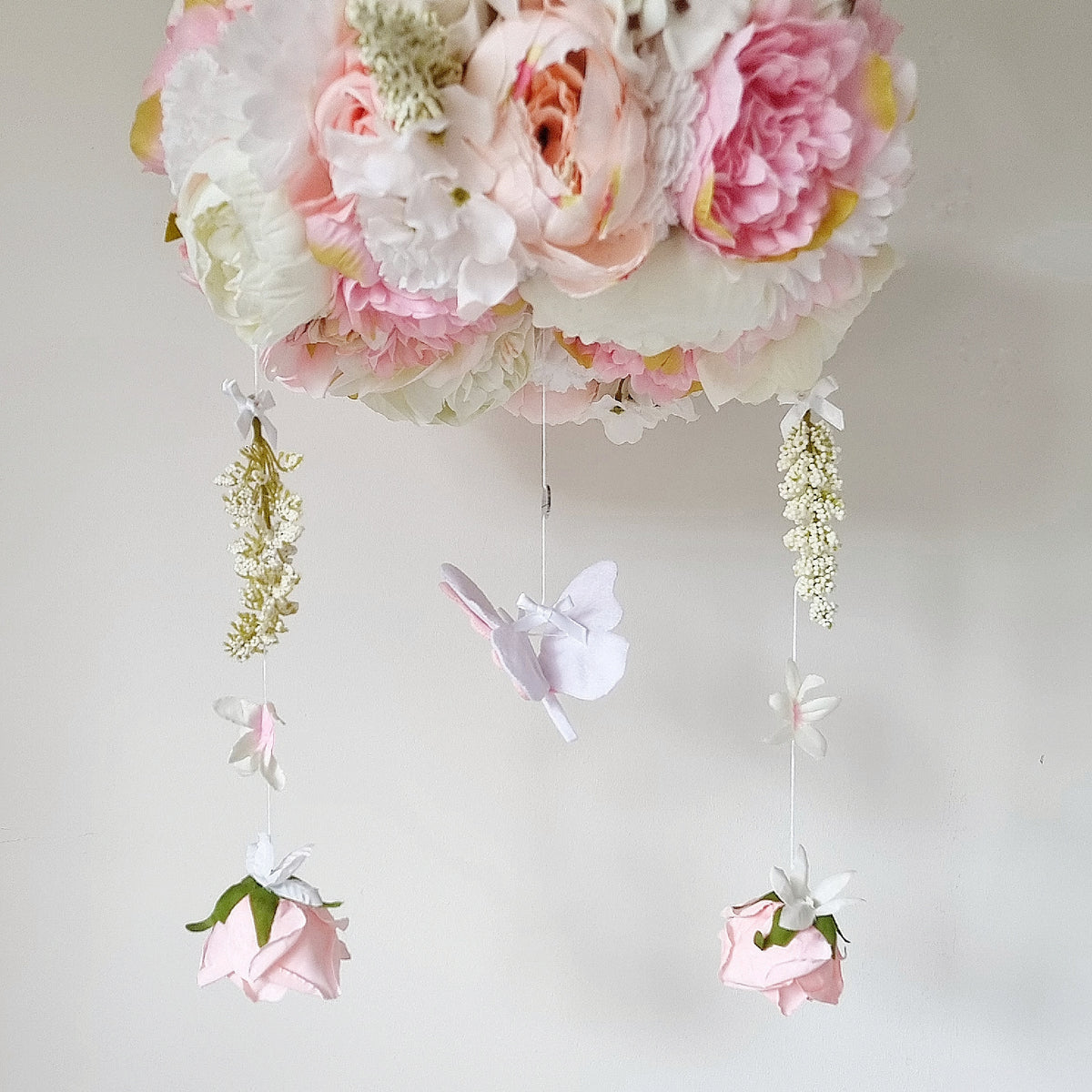 Handmade baby girl mobile featuring a floating butterfly, faux florals, and delicate trailing blossoms in pink and white.