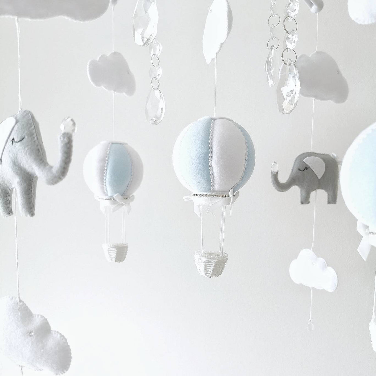 White felt clouds with floating crystal raindrops catching the light a soft finishing touch for a dreamy baby mobile