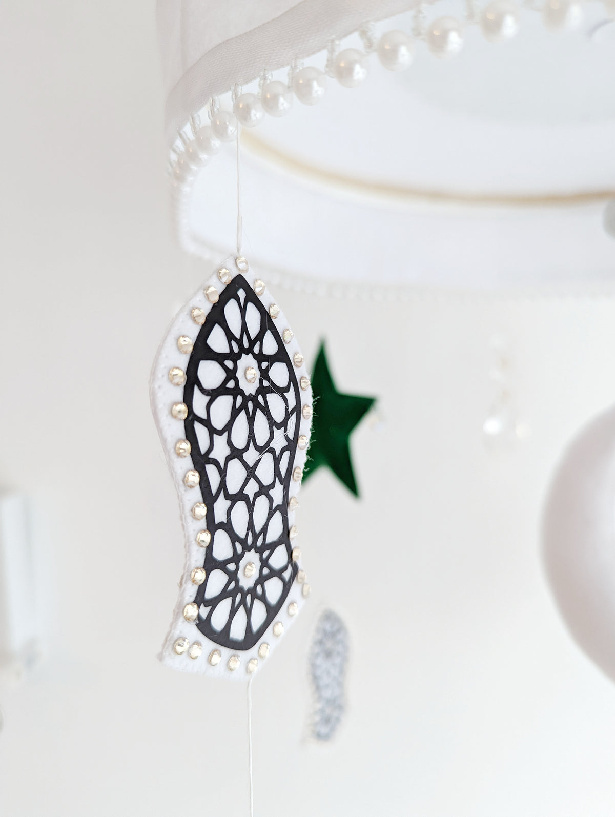 Eid-inspired baby mobile with floral mosque dome, crescent moon, and felt sandal shapes representing the Prophet’s legacy.

