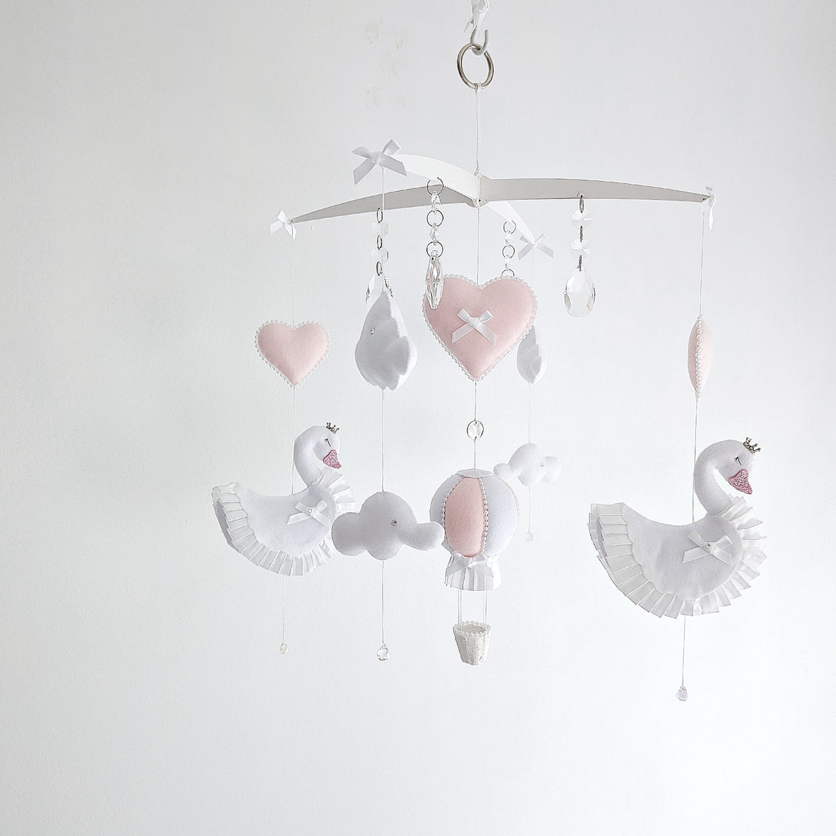 Elegant baby mobile with white swans, hearts, clouds, and a soft pink hot air balloon.