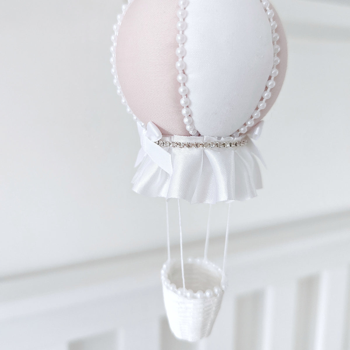 Elegant nursery mobile with cascading crystals, ivory roses, and a handmade balloon in soft pink and white.