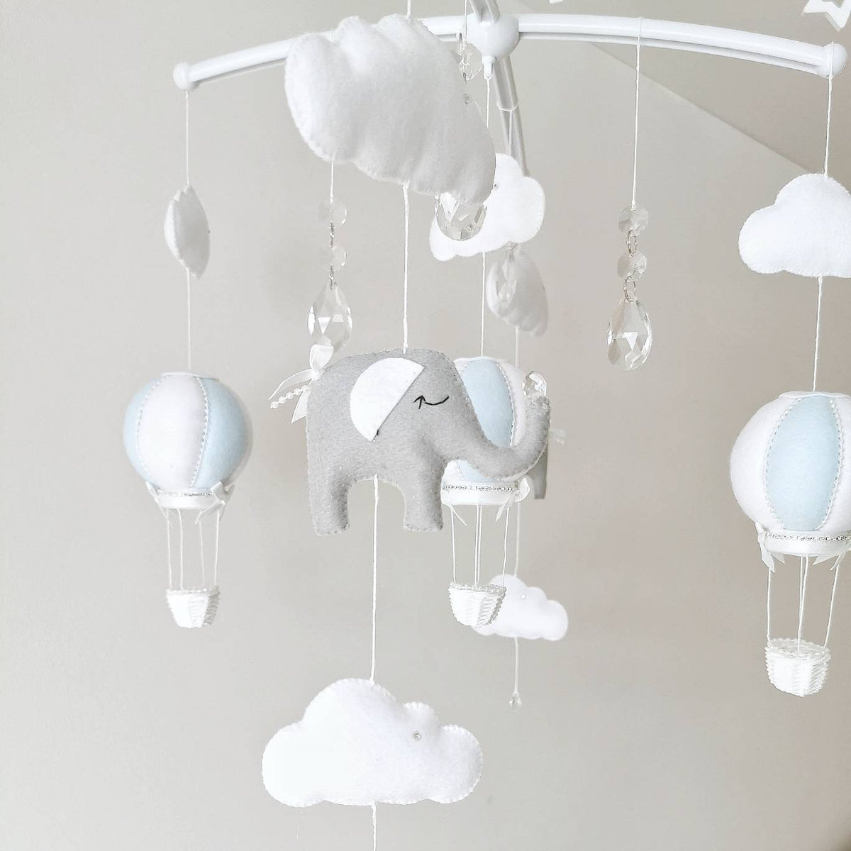 Peaceful felt elephant in soft grey with a gentle expression floating in a sky of balloons and clouds in this handmade mobile

