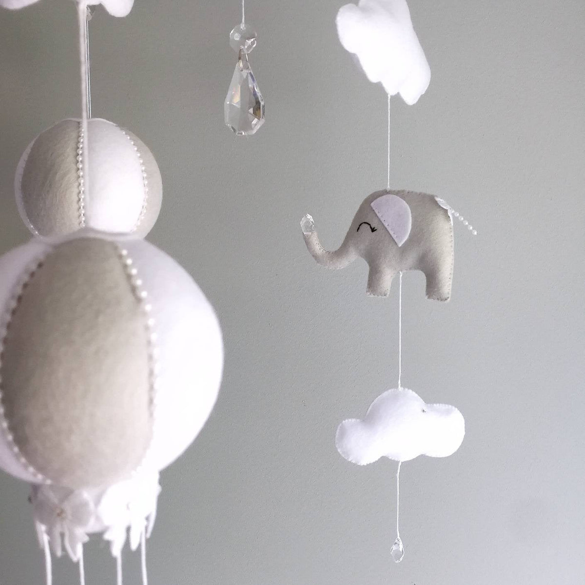 Peaceful felt elephant with soft curves and a sleepy expression, part of a safari-inspired mobile in soothing neutral tones.