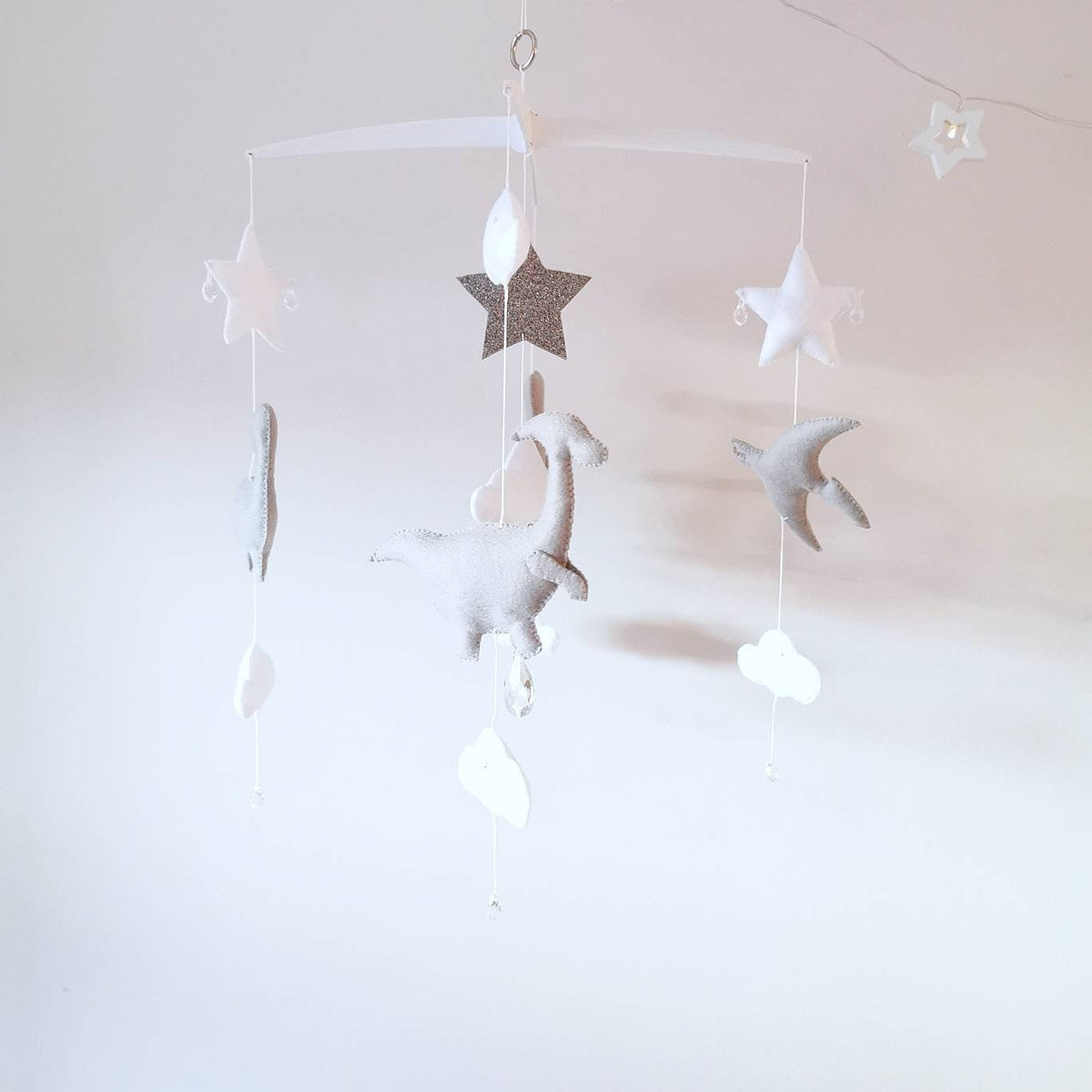 Grey dinosaur figures with star and cloud details, designed for a playful and soft nursery mobile.


