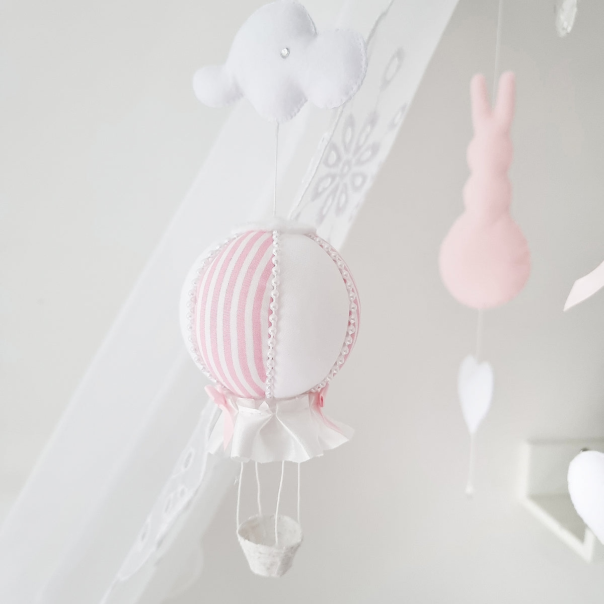 Handcrafted nursery mobile featuring pastel pink bunnies, soft hearts, and a striped hot air balloon—perfect for a baby girl nursery

