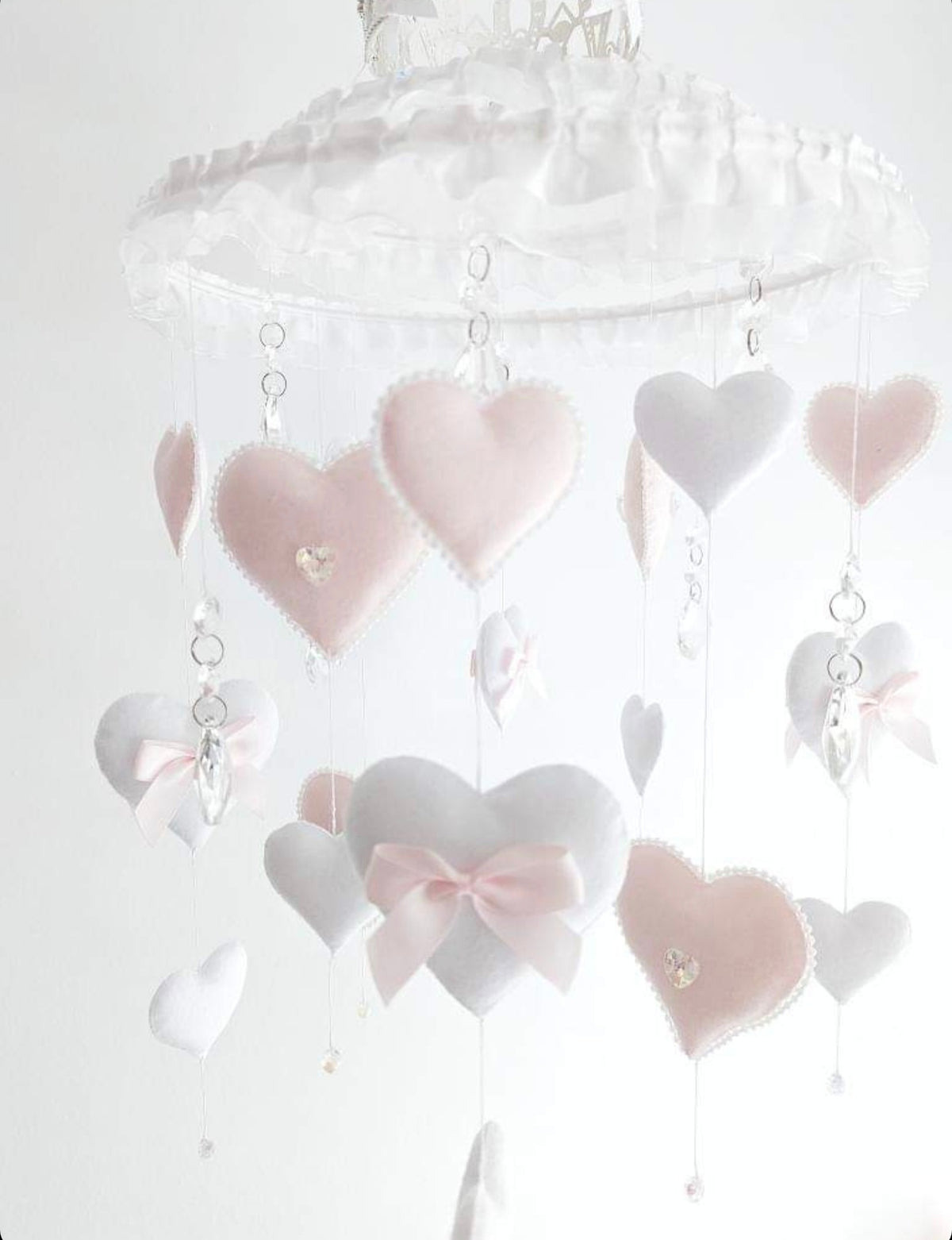 Handmade nursery mobile with felt hearts, bows, crystal drops, and a sparkling crown—perfect for a royal baby space.