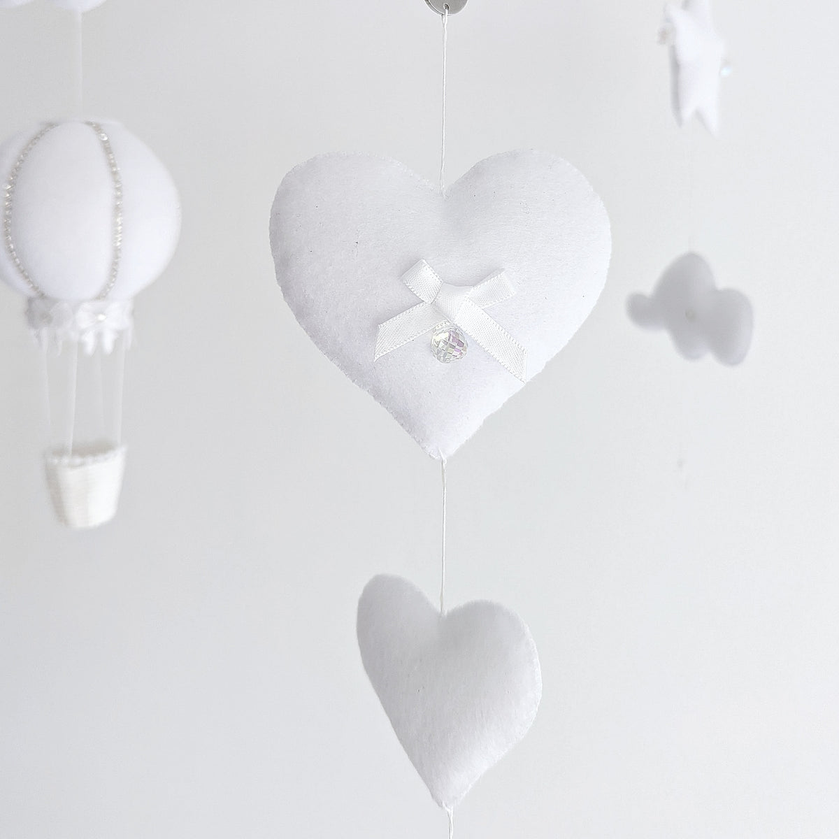 High-end nursery mobile featuring handcrafted hot air balloons, heart shapes, and soft textures for a serene and elegant space.

