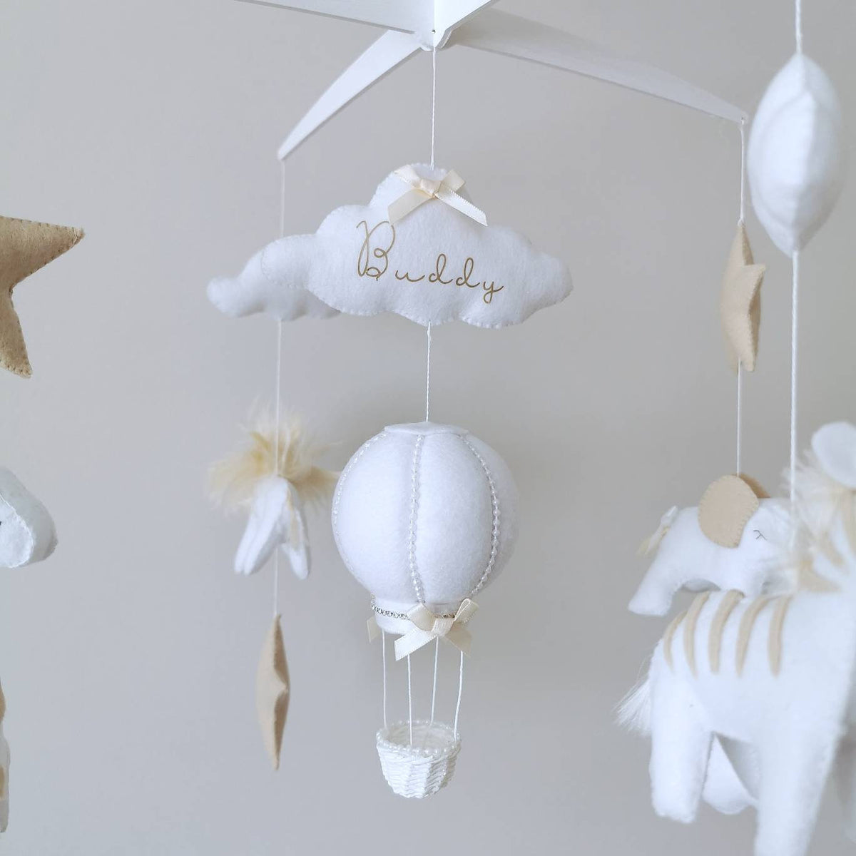 A white hand made hot air balloon, light as a lullaby, drifts between stars, capturing the wonder of adventure in this handcrafted neutral nursery mobile.

