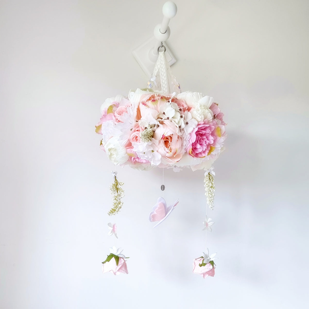Luxury baby mobile with blush pink peonies, soft white florals and a butterfly, styled in a romantic garden-inspired nursery.