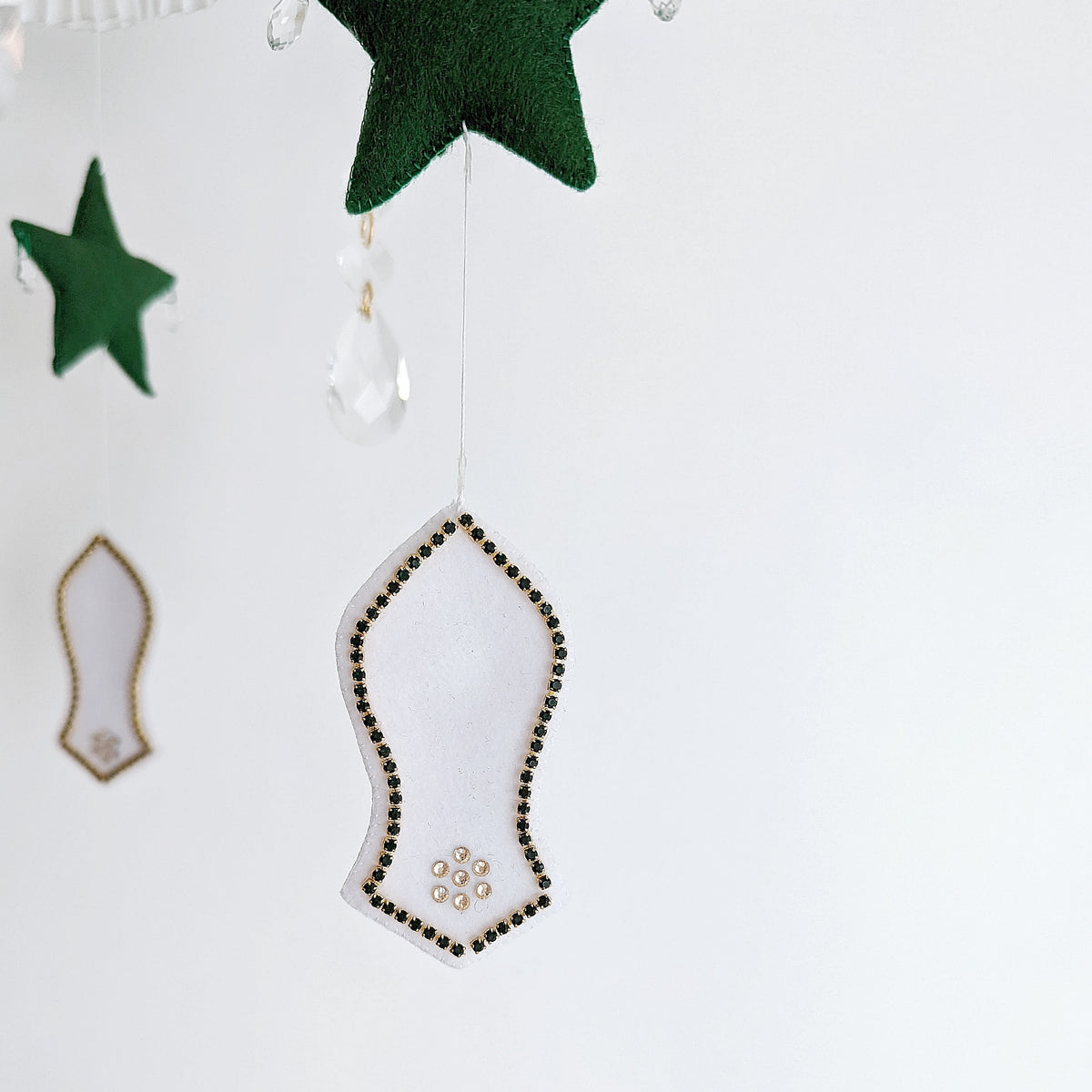 Luxury Islamic baby mobile with embroidered mosque motifs, a crescent moon, and a respectful sandal symbol honouring the Prophet Muhammad (pbuh).


