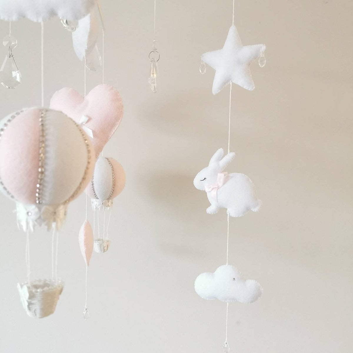 Luxury nursery mobile with plush bunny silhouettes, pink hearts, and a white and pink striped hot air balloon.
