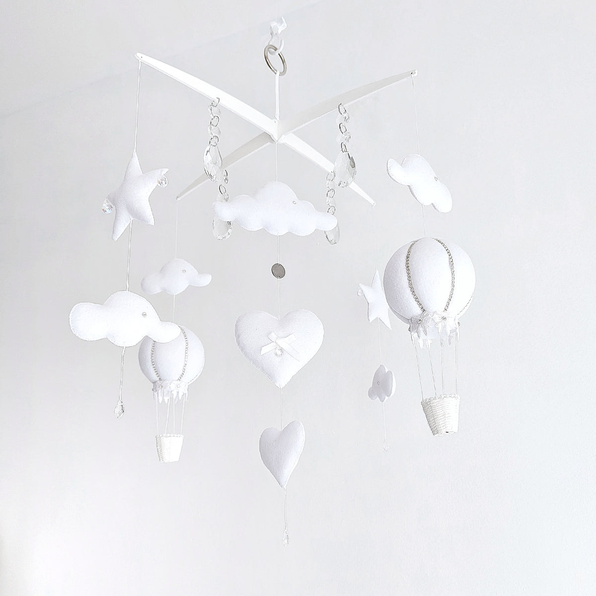 Elegant white nursery mobile featuring handcrafted hot air balloons, star details, and crystal drops for a soft sky-inspired look.