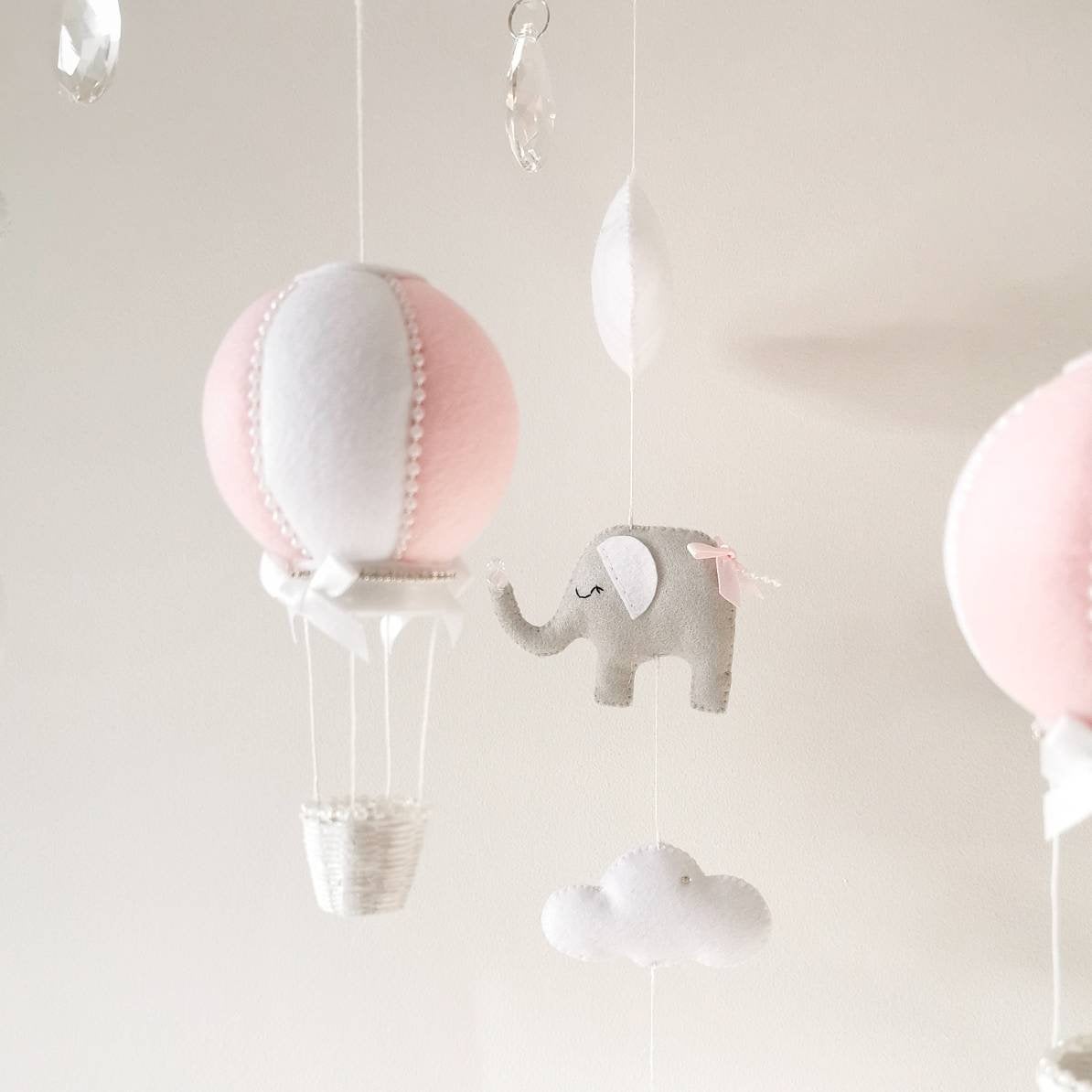 A softly floating elephant mobile in blush pink and white tones perfect for creating a gentle calming space in a baby girl’s room

