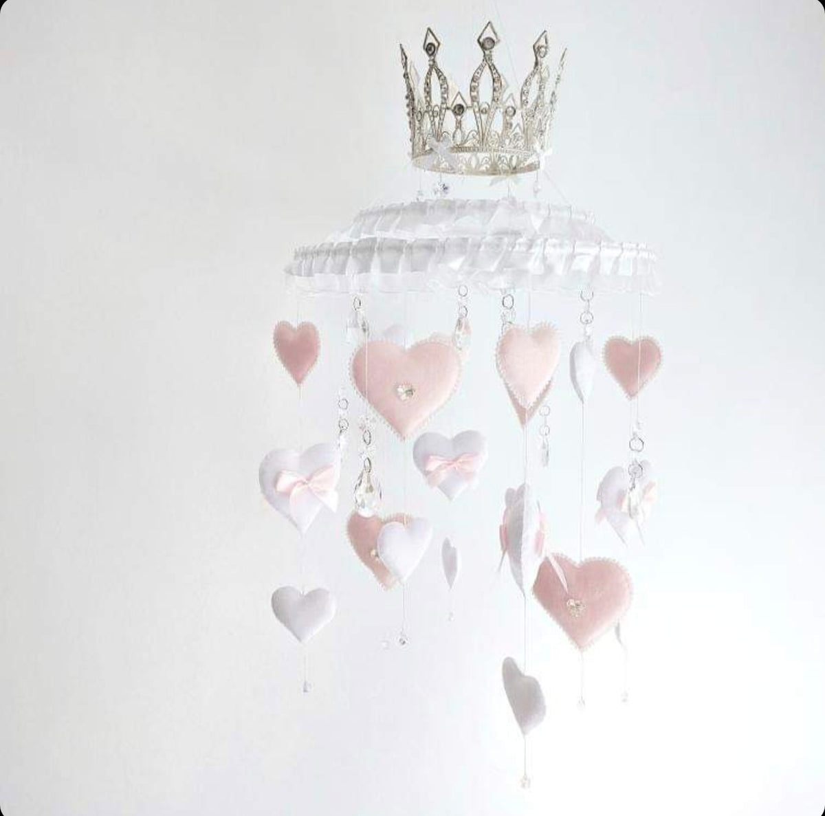 Princess-inspired baby mobile with ruffled trim, dangling hearts, and a regal crown centrepiece.

