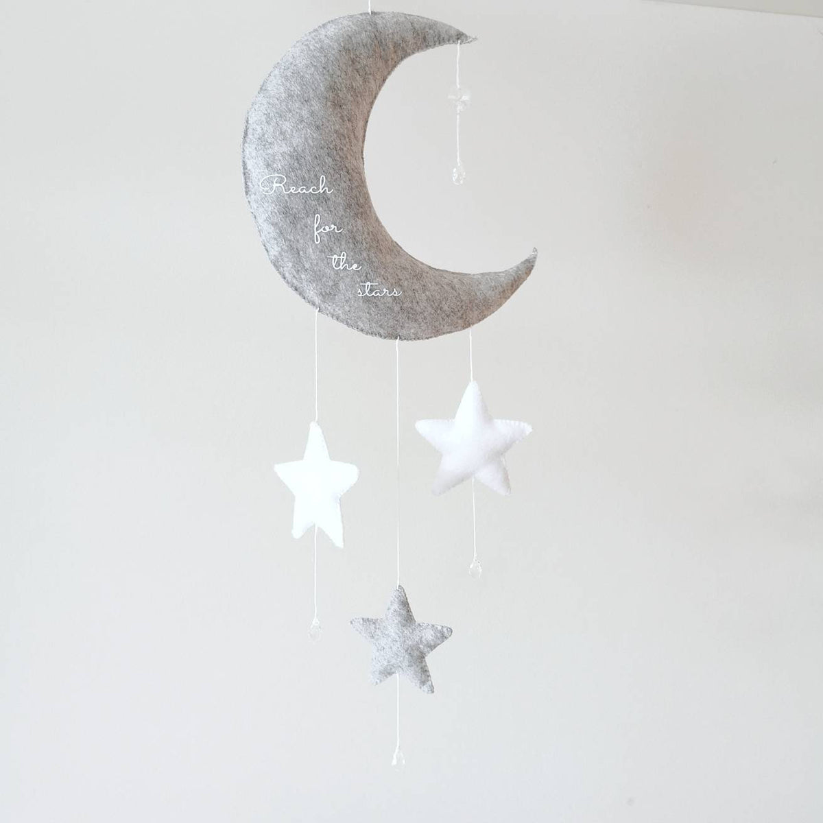 Grey crescent moon wall charm with “Reach for the stars” embroidery and stars—perfect as a baby shower or christening gift.

