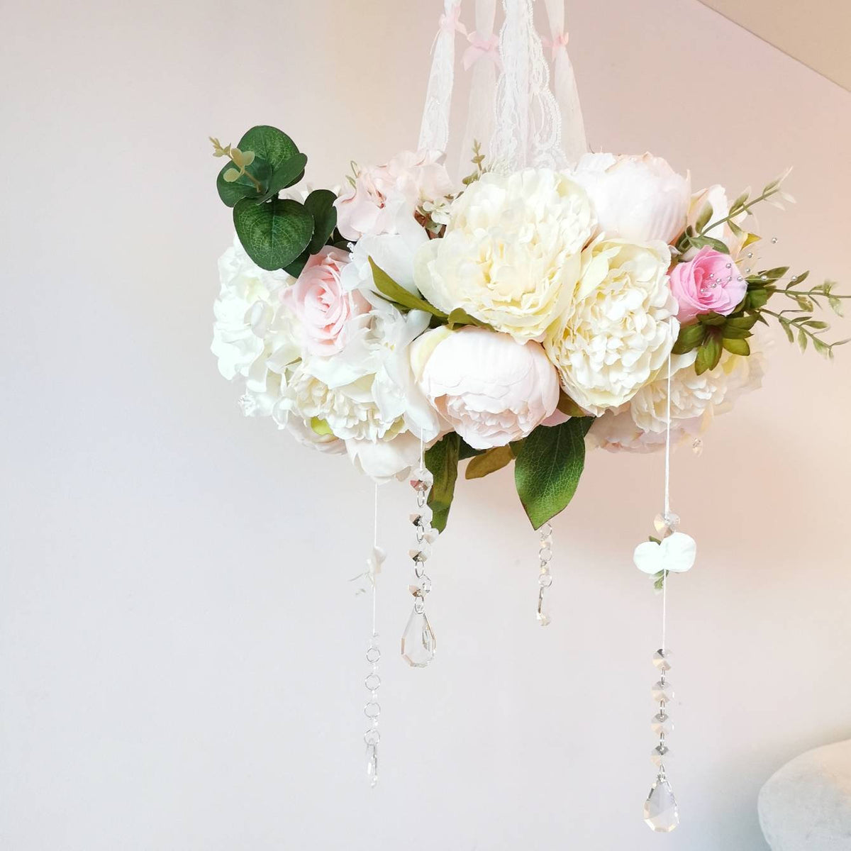 Romantic baby mobile in pink and white with floral details and a blush hot air balloon centrepiece.

