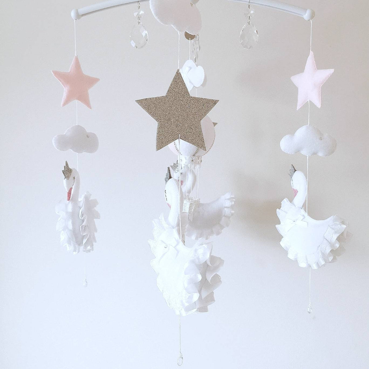 Sparkling stars and soft clouds float quietly above, adding a little stardust to this elegant handmade nursery mobile

