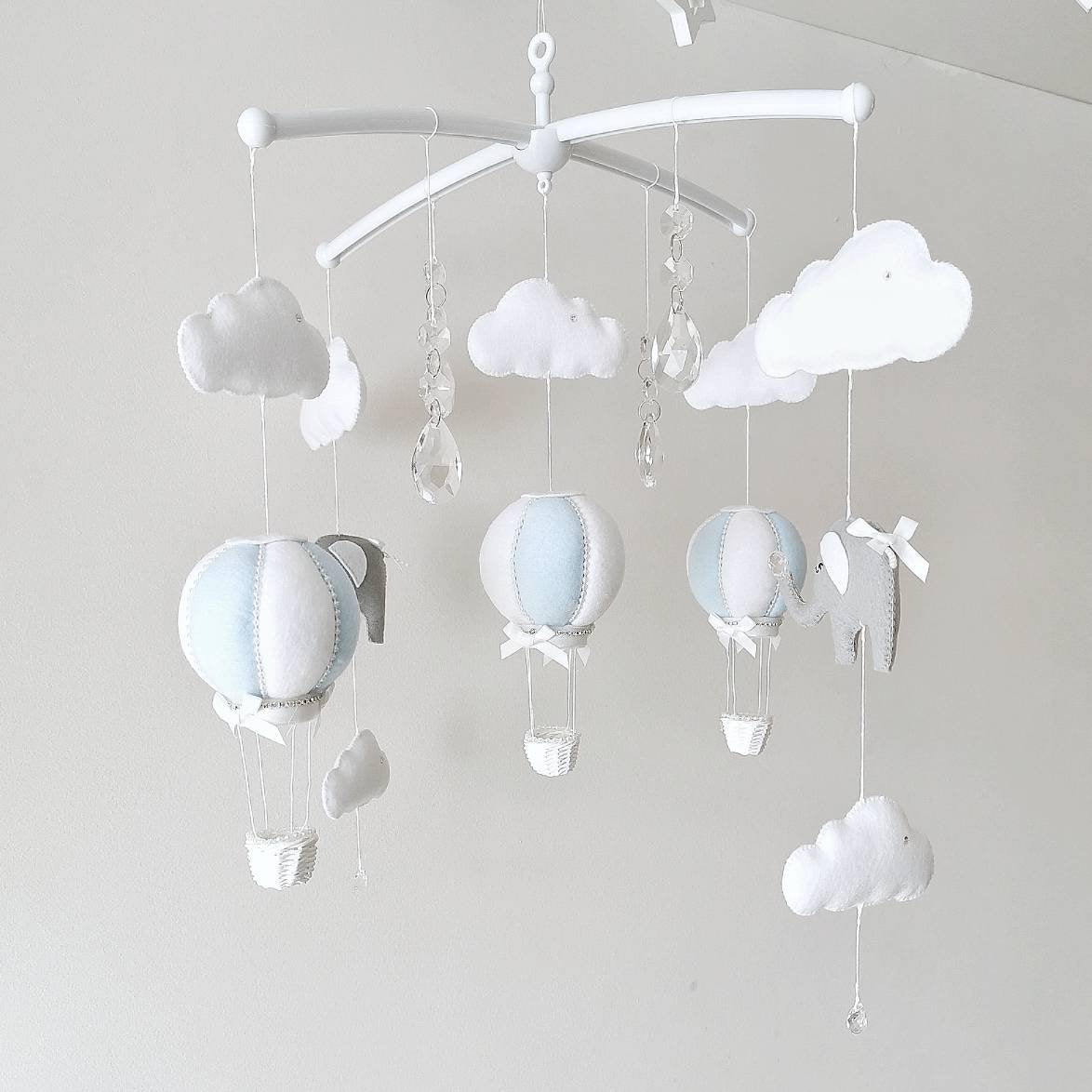 Handmade baby mobile with soft blue balloons white clouds and gentle elephants designed to bring a dreamy calm to any nursery space

