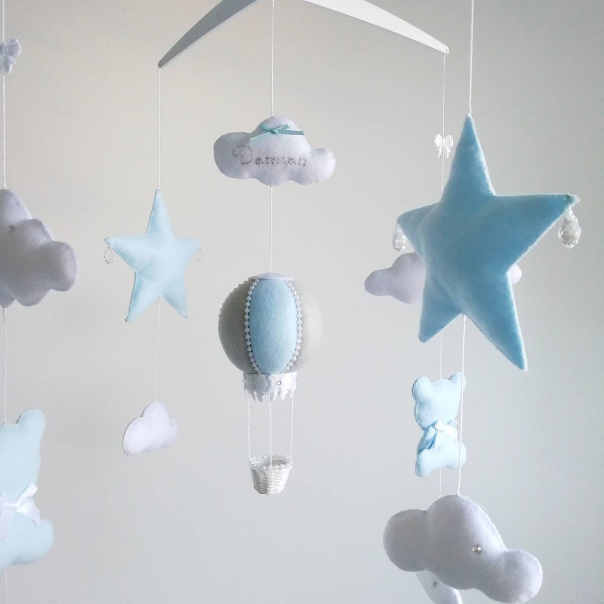 Close up of a blue star and soft white clouds from a dreamy handmade mobile for a baby boy nursery.