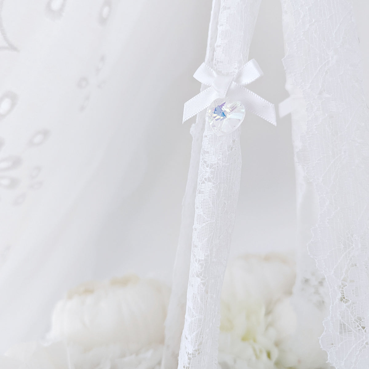 Close-up of soft blush and ivory florals forming a delicate wreath, part of a high-end baby mobile.

